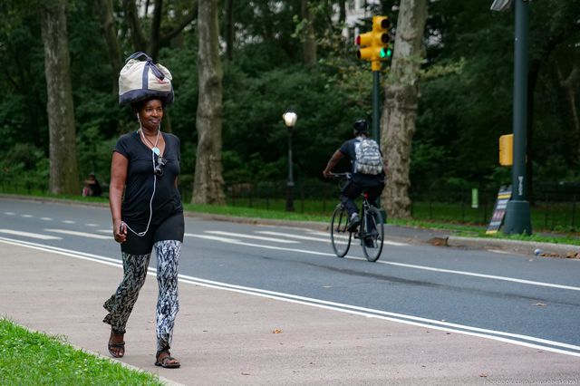 A photo of a woman carrying her bag on her head in Central Park